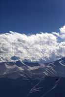 winter mountain in evening and silhouette of parachutist