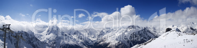 panoramic view on ski slope and cloudy mountains at sun day
