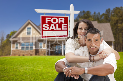 hispanic couple, new home and for sale real estate sign
