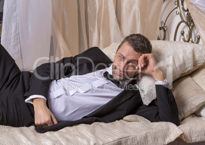 elegant playboy reclining on a bed