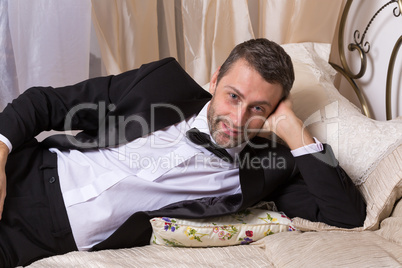 elegant playboy reclining on a bed