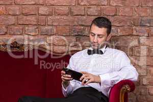 businessman lying on a settee and reading tablet