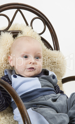 newborn child in chair with sheepskin
