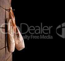 used ballet shoes hanging on wooden background