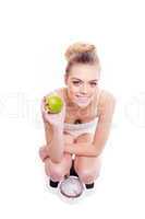 young woman with an apple on a bathroom scale