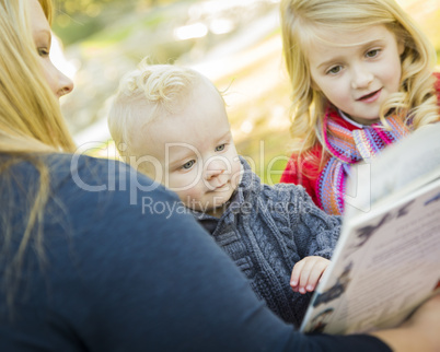 mother reading a book to her two adorable blonde children.