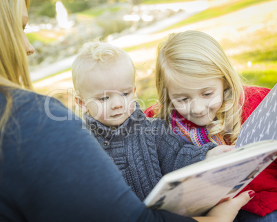 mother reading a book to her two adorable blonde children.