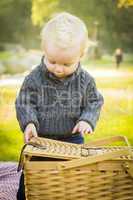 blonde baby boy opening picnic basket outdoors at the park