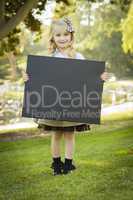 cute little blonde girl holding a black chalkboard outdoors.