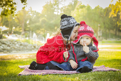 little girl whispers a secret to baby brother outdoors