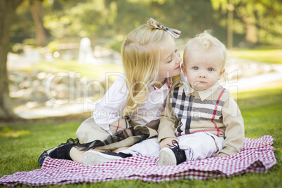 sweet little girl kisses her baby brother at the park.