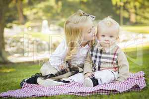 sweet little girl kisses her baby brother at the park.