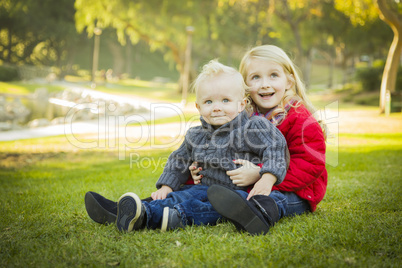 little girl with baby brother wearing coats at the park.