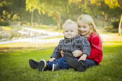 Little Girl with Baby Brother Wearing Coats at the Park.