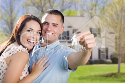 military couple with house keys in front of new home