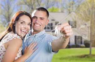 military couple with house keys in front of new home