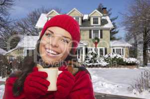 smiling woman in winter clothing holding mug outside in snow