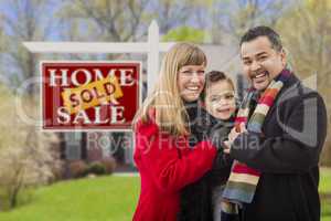 family in front of sold real estate sign and house