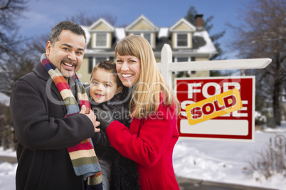 family in front of sold real estate sign and house