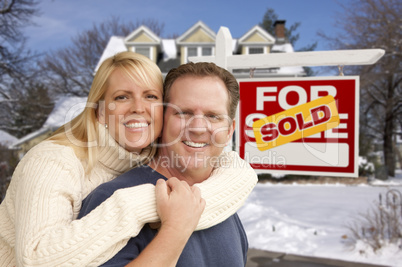 couple in front of new house and real estate sign