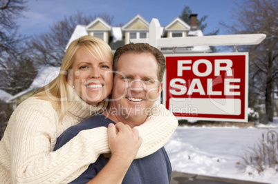 couple in front of new house and real estate sign