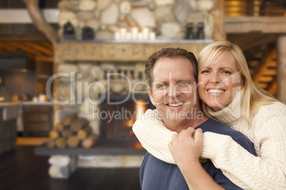 affectionate couple at rustic fireplace in log cabin