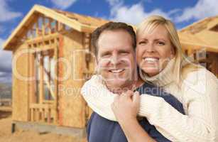 couple in front of new home construction framing site