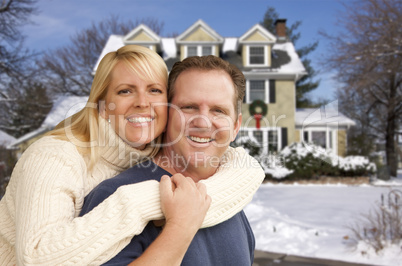 couple in front of beautiful house with snow on ground