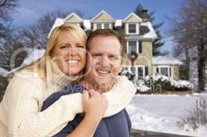couple in front of beautiful house with snow on ground