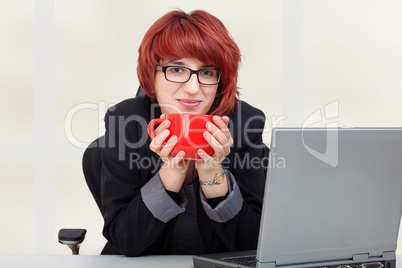 woman sitting on laptop and drinking from the cup