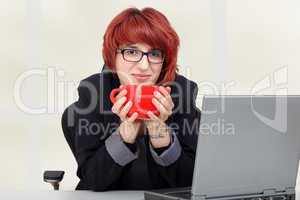 woman sitting on laptop and drinking from the cup