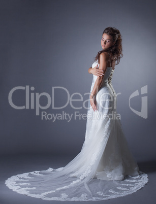 Slender brunette posing in stylish wedding dress