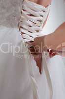 Woman's hands lace up corset on bride's dress