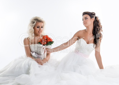 Two charming brides posing with bouquet in studio