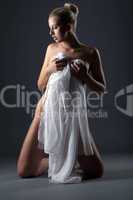 Alluring naked woman covered with white cloth
