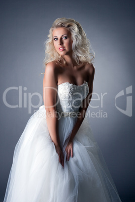 Romantic blonde posing in lush wedding dress