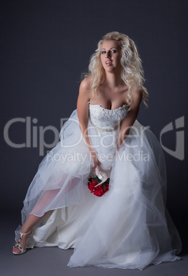 Elegant curly-haired bride posing in studio