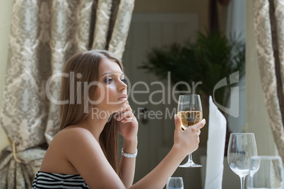 Thoughtful pretty woman posing with glass of wine