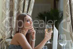 Thoughtful pretty woman posing with glass of wine