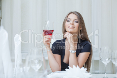 Charming smiling girl drinking wine in restaurant