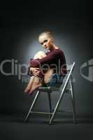 Refined model in stylish clothes sitting on chair