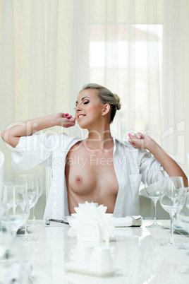 Sexy smiling girl stretches while sitting at table