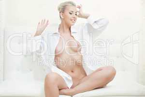 Beautiful slim model posing naked sitting on sofa
