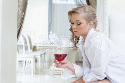 Beautiful girl thoughtfully looks at glass of wine
