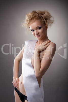 Smiling naked model with ribbon posing in studio