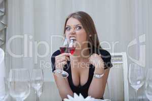 Pretty funny girl biting glass of wine, close-up