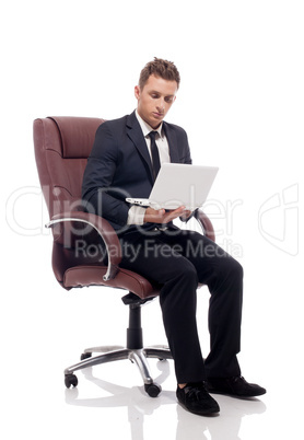 Handsome businessman sitting in chair with laptop