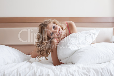 Smiling curly blonde posing with pillow, close-up