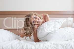 Smiling curly blonde posing with pillow, close-up