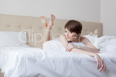 Cute young brunette with short hair posing in bed